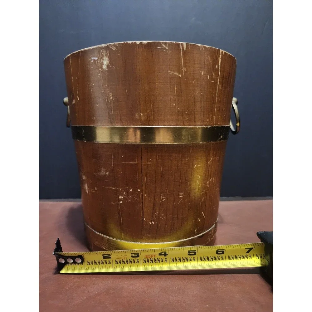 This is a vintage wood and brass barrel-style ice bucket typically measuring...